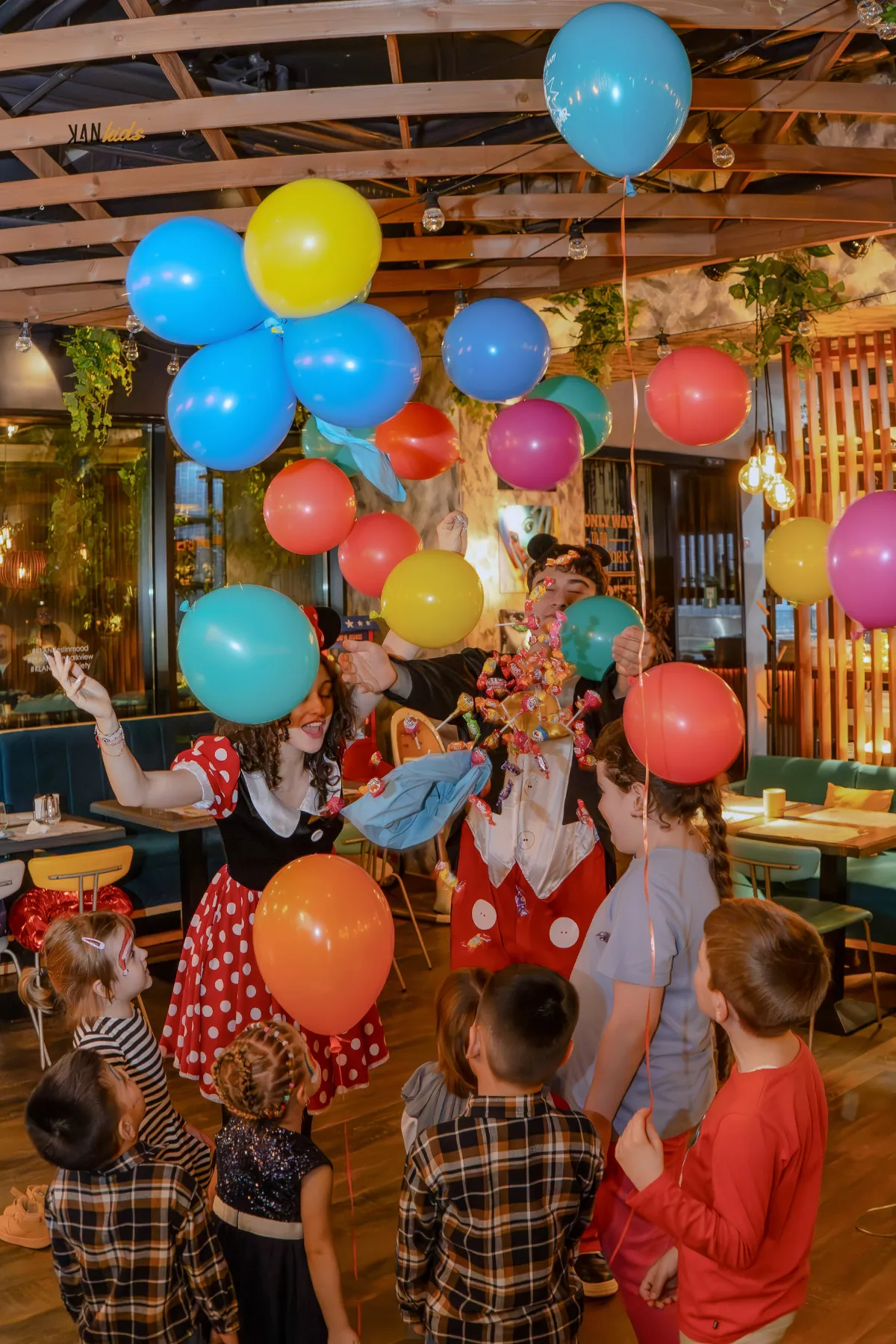 Animatori costumați și copii printre baloane colorate la o petrecere KLANkids
